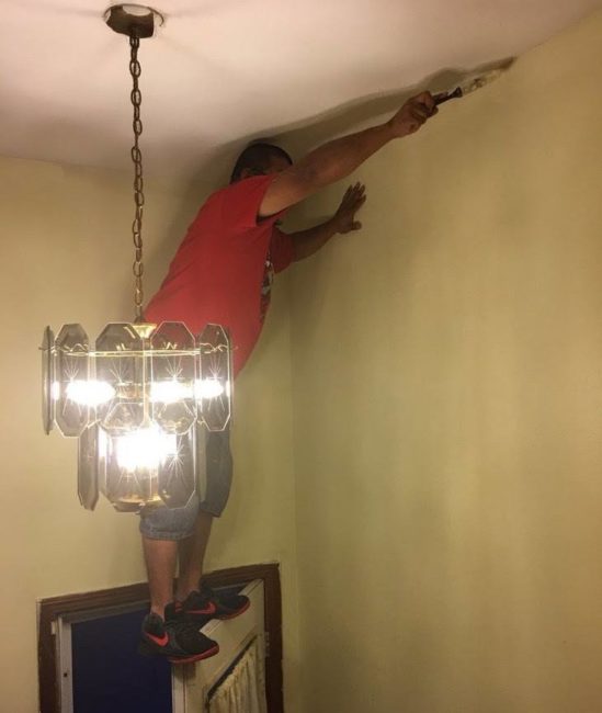 painter stands on door to paint ceiling funny