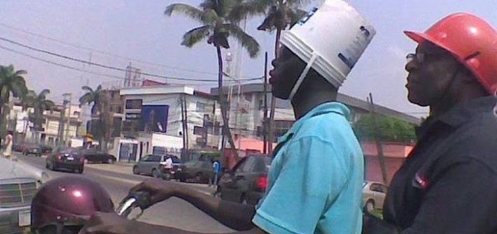 guy riding a motorcycle with a bucket on his head
