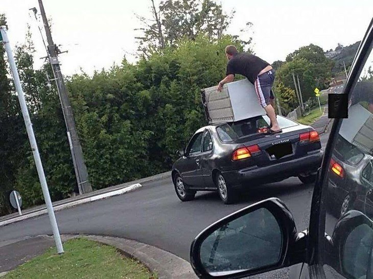 guy standing on moving car with a dresser