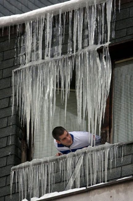 guy sticking head of window covered with icicles